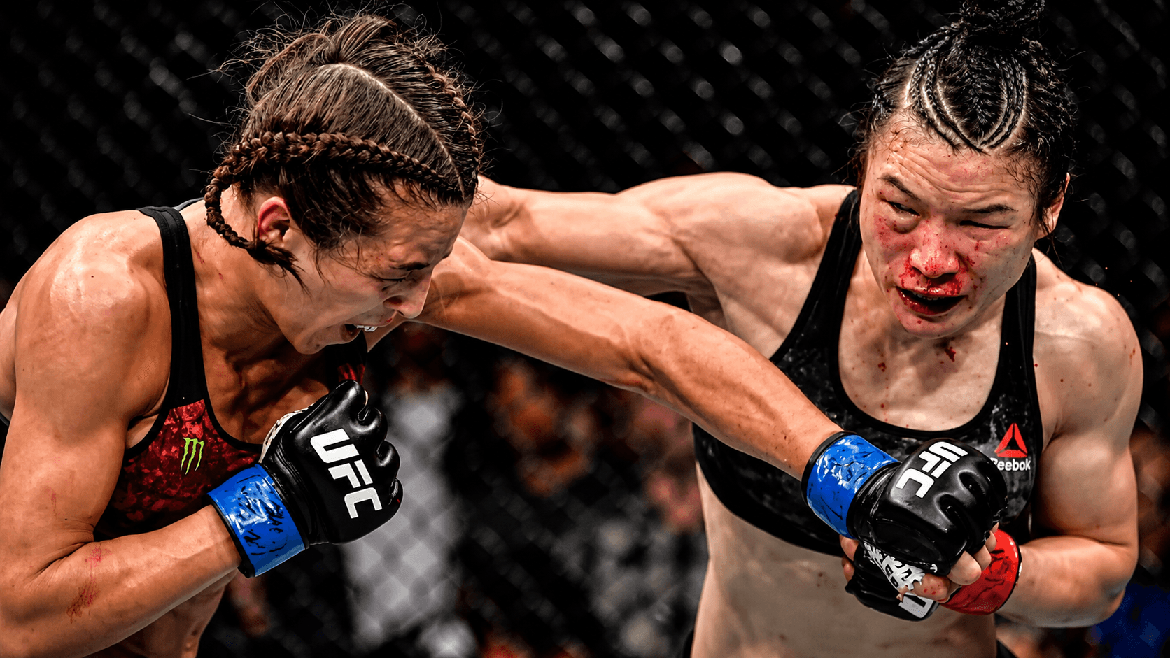 Two women exchanging punches at range in the centre of the cage.