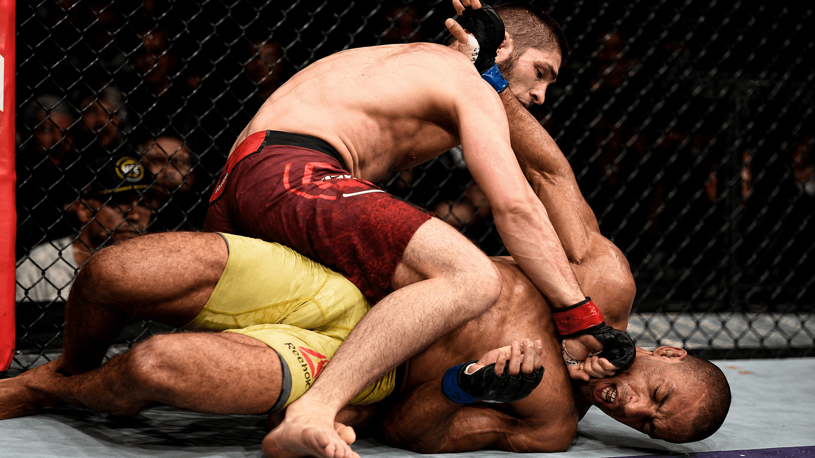 A fighter throwing punches from top position on the mat.