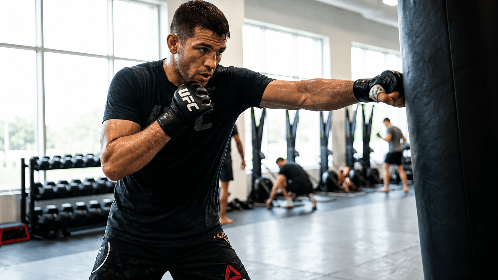 A fighter working a heavy bag in a gym, throwing a straight right hand.
