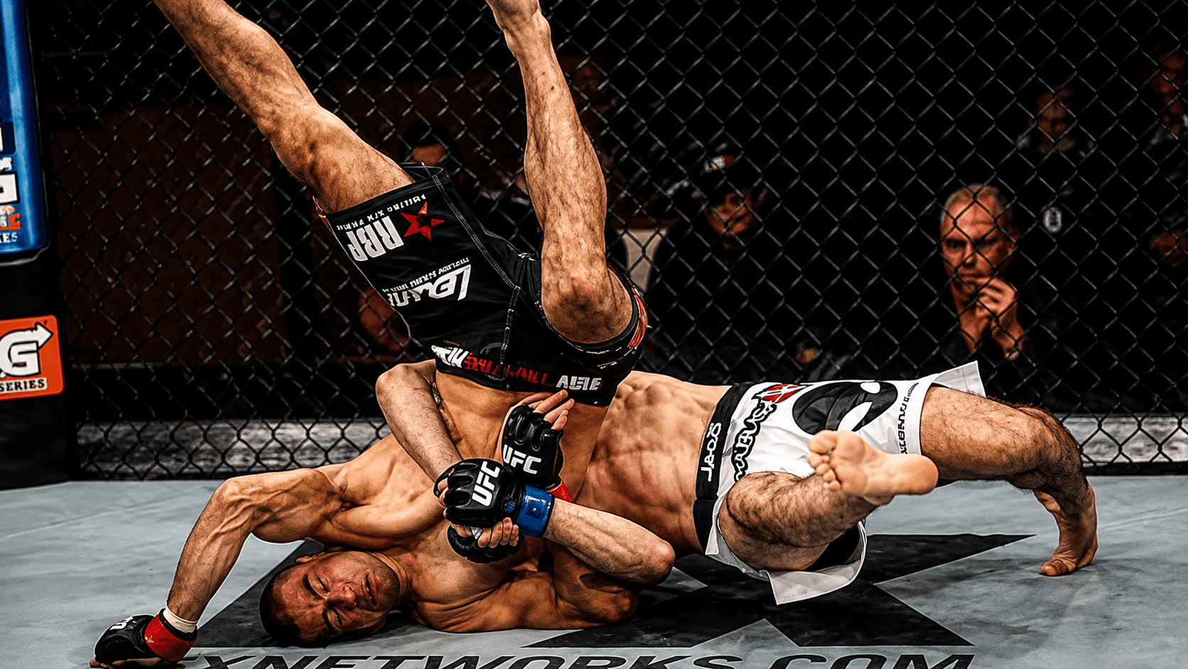 Two fighters locked in a clinch against the fence.