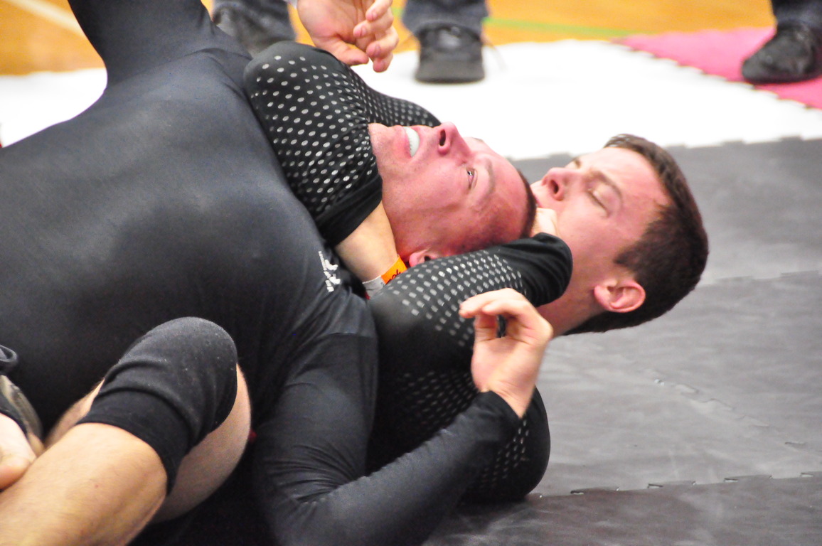 A rear naked choke sunk in from the back, the trapped fighter reaching for a tap.