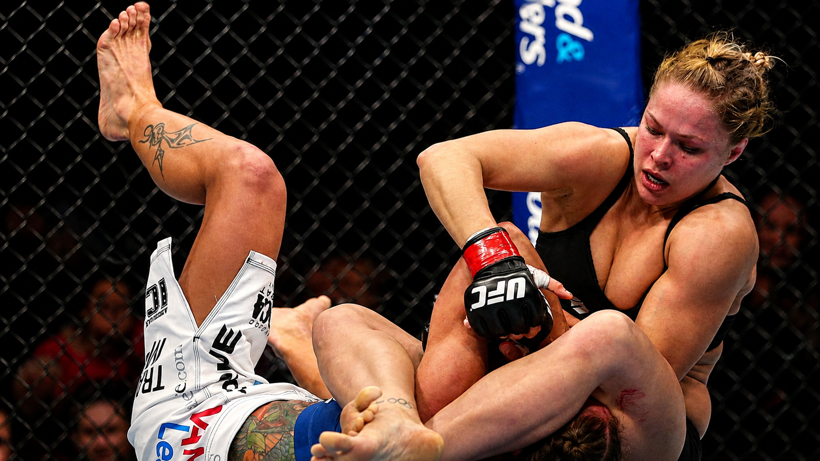 A fighter attacking an armbar from her back in a women's bout.